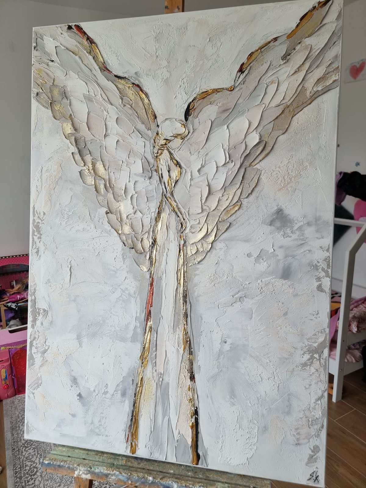 Textured painting of an angel with outstretched wings in white and gold tones on canvas
