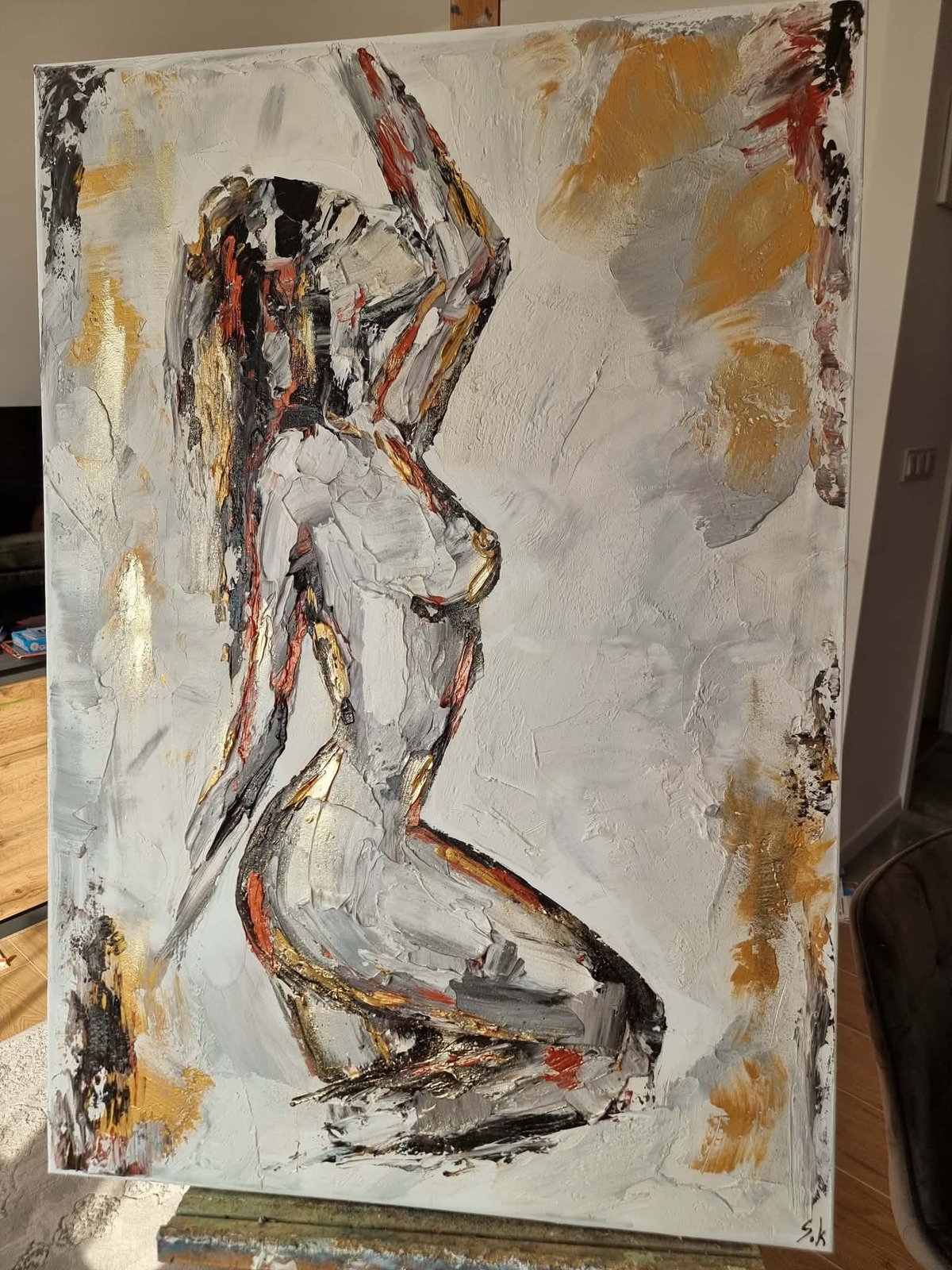 Abstract figure painting with nude seated form in black, red, and white on cream canvas with golden accents