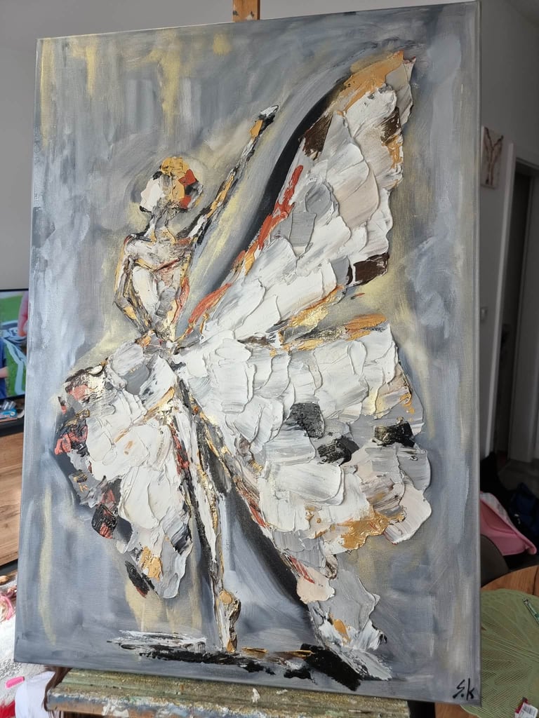 Abstract oil painting of a figure with large white wings against a gray background, displayed on an easel in a studio setting