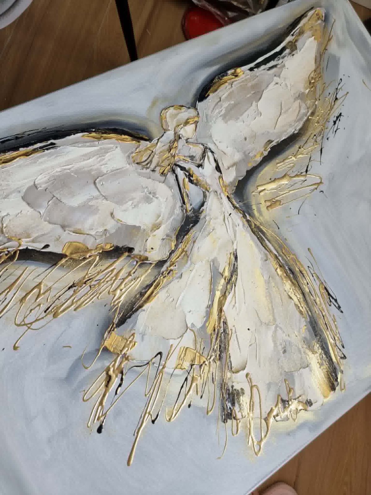 Abstract painting of an angel figure with cream and gold brush strokes on white canvas