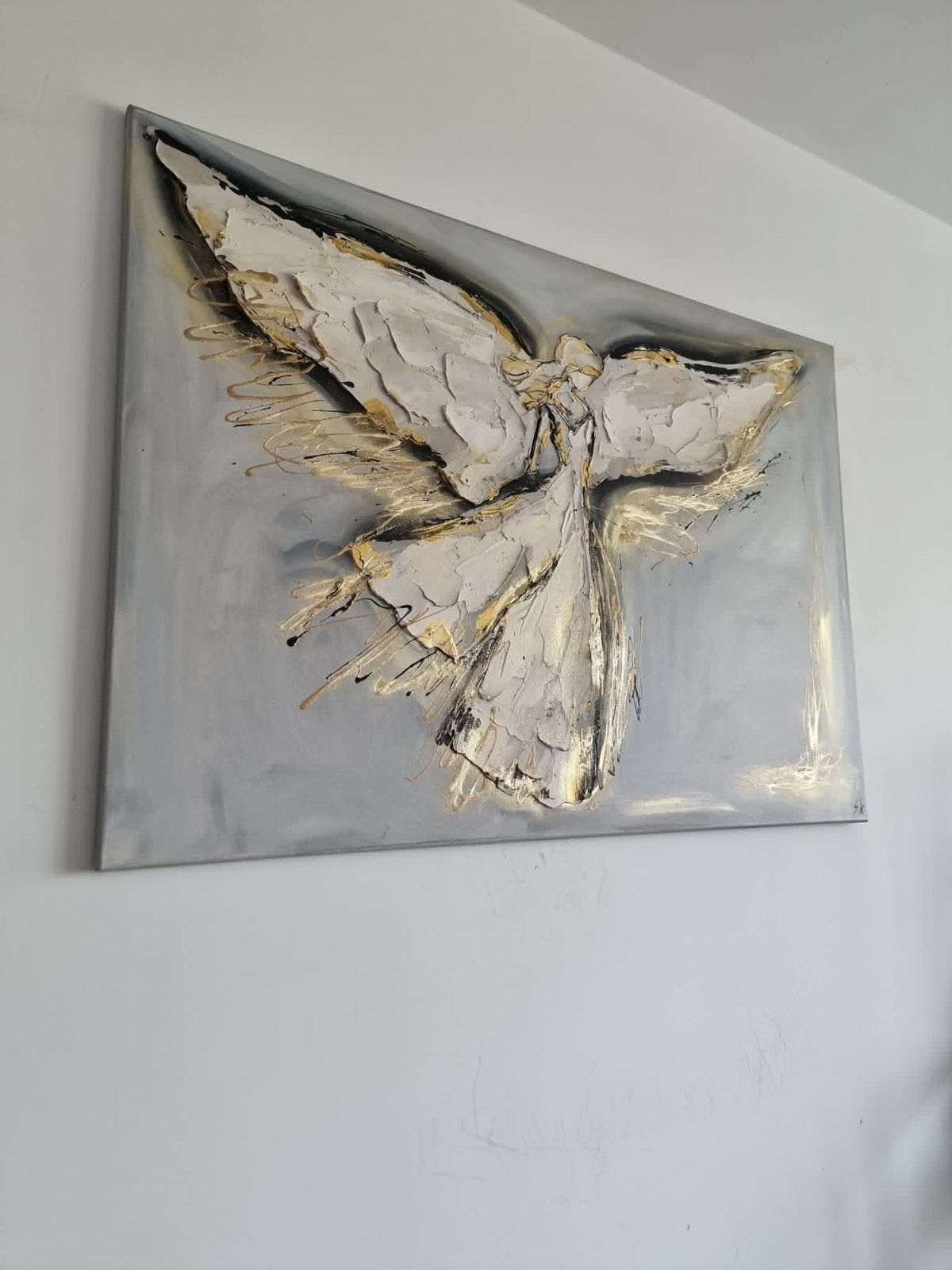 Abstract textured artwork of a white and gold bird in flight mounted on a gray canvas panel on a white wall